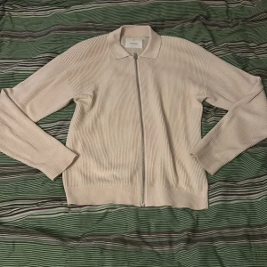 Beige ribbad tröja från Jack & Jones - Säljer en stilren beige ribbad tröja från Jack & Jones. Tröjan har en dragkedja framtill och långa ärmar, perfekt för en avslappnad look. Passar bra till både jeans och chinos. Köpte den för 650 har använt den en gång sen har den inte kommit till användning där av säljar jag den// hör av dig om du undrar något// William 