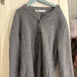 Grå kofta från Zara - Mysig grå kofta från Zara med knappar framtill. Perfekt för kyligare dagar med sin stickade design och långa ärmar. Enkel och stilren, passar till det mesta i garderoben.