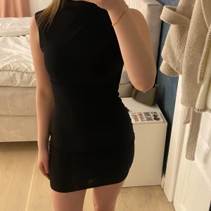 Svart tight klänning från BikBok  - Snygg svart tight klänning med ärmlös design och kort längd. Perfekt för en kväll ute eller en speciell tillställning. Enkel och stilren look som passar till många tillfällen.