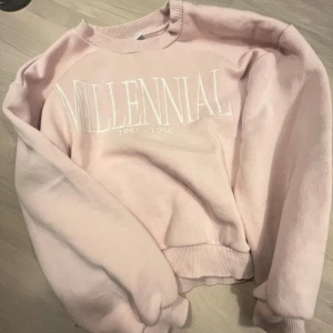 Rosa sweatshirt från Lindex - Säljer en rosa sweatshirt från Lindex med texten 'Millennial 1981-1996' tryckt på framsidan. Tröjan har långa ärmar och ribbade muddar vid hals, ärmslut och nederkant. Perfekt för en avslappnad stil.