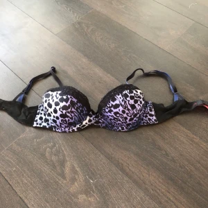 Leopardmönstrad bh från Betsey Johnson - Snygg bh från Betsey Johnson med leopardmönster i svart och svarta spetsdetaljer. Osäker på storlek…tror det står 32B vilket borde motsvara 70B!