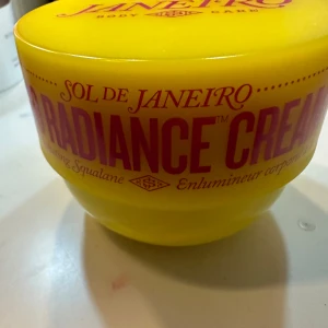 Sol de Janeiro Radiance Cream testad 1 tillfälle , 240 ml  - Sol de Janeiro Radiance Cream i en ljusgul burk. Krämen innehåller squalane och är designad för att ge huden en strålande lyster. Perfekt för att återfukta och ge huden en mjuk känsla., 240 ml testad 1 tillfälle 