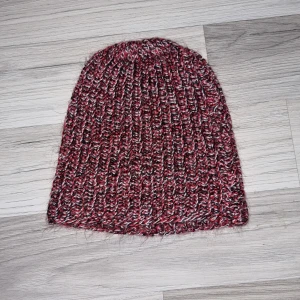 Röd och svart stickad mössa - Säljer en snygg röd och svart stickad mössa med ribbad design. Perfekt för att hålla värmen under kyliga dagar. Mössan har en skön passform och är Hemmastickad.