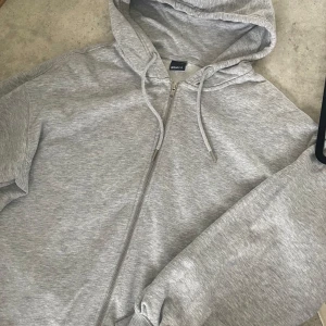 grå ziphoodie från gina tricot - mysig grå ziphoodie från Gina Tricot i bra skick. den har långa ärmar och ribbade muddar. enkelt och stilrent plagg som passar till det mesta! (väldigt oversized men riktigt skön)