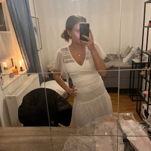 Vit klänning från Bubbleroom - Säljer en söt vit klänning från Bubbleroom student klänning  med korta ärmar och v-ringning. Klänningen har en luftig och lätt design, perfekt för varmare dagar. Den har en fin struktur och faller fint över kroppen.
