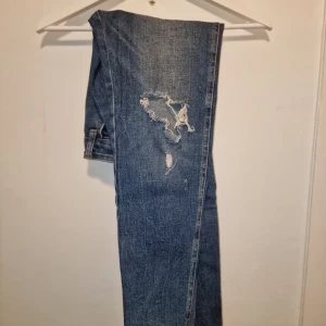 Blå jeans med slitningar - Snygga blå jeans med coola slitningar på framsidan. Perfekta för en casual look.