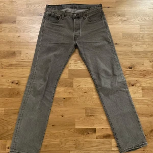 Grå Levis 501 jeans - Säljer ett par klassiska grå Levis 501 jeans. De har en rak passform och är tillverkade i slitstarkt denim. Perfekta för en stilren look med fem fickor och knappgylf.