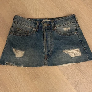 Jeanskjol från H&M Conscious - Snygg jeanskjol från H&M Conscious i jeans blå färg. Kjolen har slitna detaljer framtill. För liten för mig.