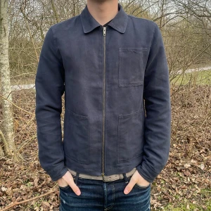 Mörkblå overshirt från Dressmann - Säljer en stilren mörkblå overshirt från Dressmann. Jackan har en dragkedja framtill och en klassisk krage. Den är långärmad och har en bröstficka för extra stil. Perfekt för en avslappnad look.