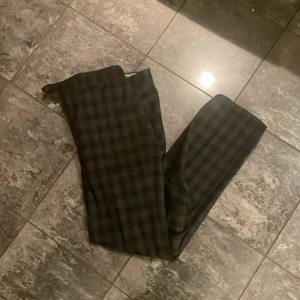 Rutig byxa i mörka toner - Snygga byxor med ett diskret rutmönster i mörka färger. Perfekta för en stilren look. Byxorna har en rak passform och är tillverkade i ett mjukt material för extra komfort.