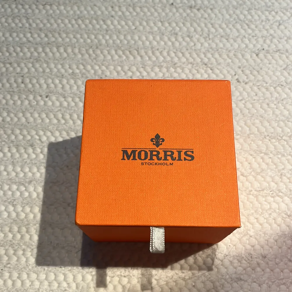 Elegant svart klocka från Morris med stilren design. Klockan har en svart urtavla med subtila markeringar och ett datumfönster. Armbandet är i svart material som ger en modern look. Perfekt för den som söker en tidlös accessoar.. Asusteet.
