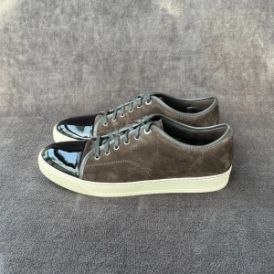 Lanvins - Snygga bruna sneakers i mocka med en glansig svart tå och vita sulor. Skorna har snörning och en stilren design som passar perfekt för en avslappnad look. Storlek 46/ Uk 12