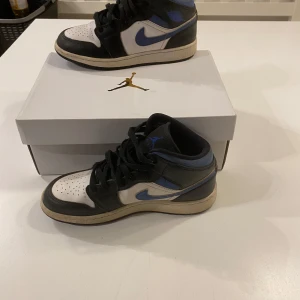 Nike Air Jordans i svart och blått - Snygga Nike Air Jordans i svart och blått med vit bas. Skorna har klassisk snörning och en ikonisk design. Perfekta för dig som vill ha en stilren och sportig look.