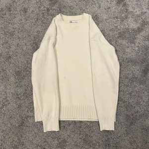 Vit stickad tröja från Zara - Säljer en stilren vit stickad tröja från Zara. Tröjan har en klassisk rund hals och långa ärmar med ribbade muddar. Perfekt för en minimalistisk look. Passar bra till både jeans och chinos.