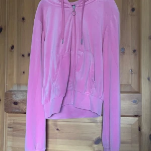 Rosa sammetshoodie med dragkedja - Säljer en mjuk och bekväm rosa hoodie i sammet med dragkedja framtill och justerbar huva. Perfekt för en avslappnad stil.