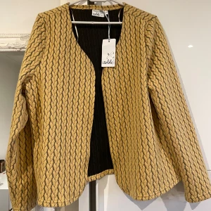 Gul mönstrad cardigan jacka från Isolde - Säljer en unik cardigan jacka från Isolde i gul nyans med ett snyggt rutmönster. Helt ny!