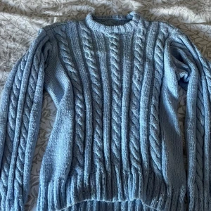 Ljusblå kabelstickad tröja - Supermysig ljusblå kabelstickad tröja med rund hals och långa ärmar. Tröjan har ett klassiskt flätmönster över hela plagget och breda ribbade muddar vid ärmslut och nederkant. Finns tyvärr inga lappar i tröjan, men uppskattar den som storlek L eller mindre. Använd fåtal gånger, inte nopprig. Skriv för mer info eller bilder! 💕