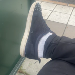 Mörkblå Loubs/ Christian louboutins - Säljer ett par mörkblå sneakers från Christian louboutin med spikar och klassisk röd sula. Skorna har snörning, platt sula och är gjorda i mocka. Storlek 46 några defekter som en tappad spik och slitage vid snörningen box kommer inte med! 