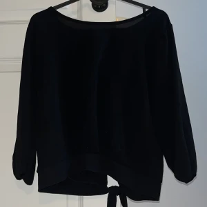 Svart tröja med knyt från MyHailys - Svart tröja från MyHailys i storlek XL. Tröjan har en rundad hals och ett snyggt knyt baktill vid nederkanten. 