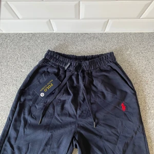 Mörkblå shorts Polo Ralph Lauren - Mörkblå mjukisbyxor från Polo Ralph Lauren med elastisk midja och snörning. Klassisk röd broderad logga på benet. Sköna byxor i bomull, perfekta för chill dagar. Snygg och enkel design med fickor på sidorna. Perfekta till hösten