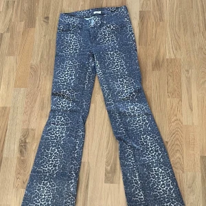 Leopardmönstrade bootcut jeans från Nelly - Snygga blå bootcut jeans från Nelly med leopardmönster. Jeansen har normal midja, klassiska fem fickor och dubbla knappar framtill. Materialet är jeans med stretch för extra komfort. Perfekta för dig som vill sticka ut med en cool look.