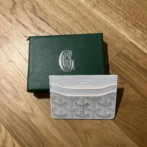 plånbok med mönster - Snygg och stilren vit plånbok med klassiskt grafiskt mönster i grått. Plånboken är tunn och smidig, perfekt för kort och cash. Kommer i original grön ask med logga. Lyxig vibe och riktigt clean design.