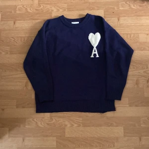 Mörkblå stickad tröja från Ami - Säljer en mörkblå stickad tröja från Ami med ett stort vitt hjärta och bokstaven A broderat på bröstet. Jag säljer den för behöver inte den faktist men den är jätte fin och är i jätte bra skick. 