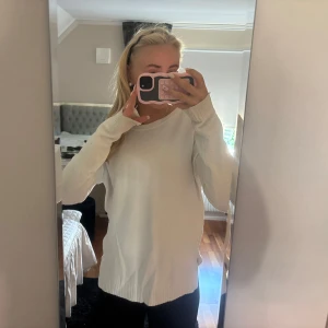 Vit stickad tröja med rund hals - Enkel och stilren vit stickad tröja med rund halsringning och långa ärmar. Den har även en slits på varje sida! Och är lite mera figur sydd en vanliga stickade tröjor, och den är otroligt varm! Köpte den på vila!