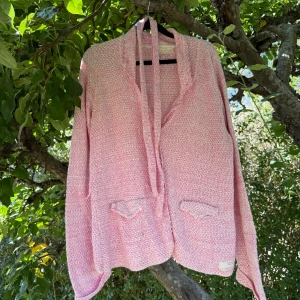 Rosa stickad kofta med knyt - Säljer en rosa och vit stickad kofta från Odd Molly med snyggt knyt framtill och två små fickor. Koftan har långärmad passform och ett mjukt, strukturerat material som känns chill och cozy. Perfekt för dig som gillar färg och vill ha något unikt i garderoben. Storlek 3 som enligt deras storleksguide motsvarar en storlek L.  Fint skick, men tyvärr finns det anmärkningar. Ena bandet som ska vara stöd till midjebandet har gått av. Kan finnas någon lite fläck. 