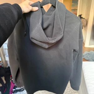 Svart hoodie från Hugo Boss - Säljer en svart hoodie från Hugo Boss med broderad logga framtill. Tröjan har huva med snörning och en klassisk känguruficka. Perfekt för dig som gillar stilrena och bekväma plagg med premiumkänsla.