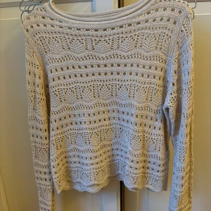 Beige stickad tröja JDY med hålmönster - Supersöt beige stickad tröja från JDY med båtringad hals och lång ärm. Tröjan har ett detaljerat hålmönster som ger en luftig och trendig look. Perfekt att styla med jeans eller kjol för en chill vibe.