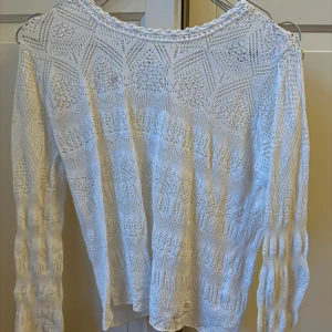 Vit spetskofta/tröja från Odd Molly - Superfin vit tröja (eller kofta) från Odd Molly med vackert spetsmönster och dekorativa knappar framtill. Långärmad och stickad i bomull, perfekt för lager på lager. Snygga virkade detaljer längs kanterna ger en romantisk vibe.