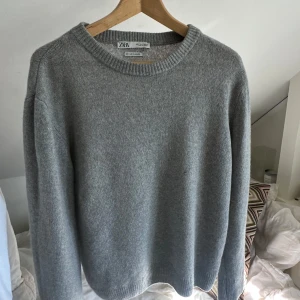 Kashmirtröja  från Zara - Enkel och stilren grå Kashmirtröja från Zara med rund halsringning och långa ärmar. Tröjan har en klassisk passform och ribbade muddar vid ärmslut och nederkant. Perfekt för lager-på-lager och chill vardagsstil.