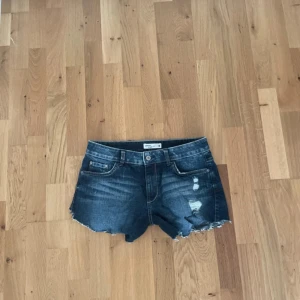 Mörkblå jeansshorts med slitningar - Snygga mörkblå jeansshorts från Bik Bok med råa kanter och slitna detaljer framtill. Klassisk femficksmodell och knappgylf. Perfekta för varma dagar och en avslappnad stil.