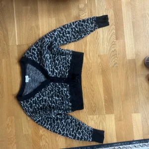 Gråsvart leopardmönstrad kofta & Other Stories - Säljer en snygg kofta från & Other Stories med leopardmönster i grått och svart. Koftan har v-ringning, knappar framtill och långa ärmar. Materialet är mjukt och stickat perfekt nu till hösten!!😊😊