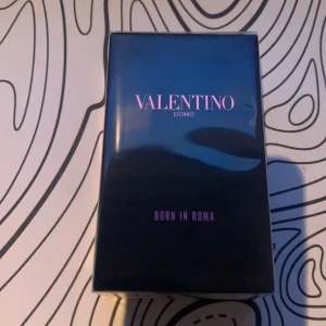Valentino Uomo Born In Roma parfym 50 ml  - Säljer en lyxig parfym från Valentino, Uomo Born In Roma. Förpackningen är stilren och svart med rosa text, och parfymen är känd för sin eleganta och moderna doft. Perfekt för dig som vill sticka ut med en exklusiv signaturdoft.