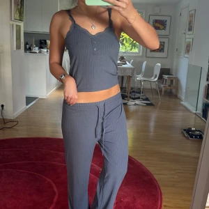 Mörkgrå ribbad linnetopp med spets matchande byxor  - Pyjamas set. En mörkgrå ribbad linnetopp med smala axelband och v-ringning dekorerad med spets med matchande byxor 