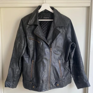 Svart skinnjacka (begagnad äkta skinn)  - Svart skinnjacka i äkta skinn, tidigare köpt på IJ-Hallen i Amsterdam. Väldigt slittålig med några tecken av användning som kom till innan jag köpte den på marknaden. Ger en ruff och cool känsla! Är storlek XL men för en person som vanligen använder M blir det en mer oversize look.