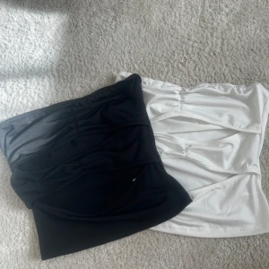 Svart och vit bandeau tubtopp med cutouts - Två bandeau tubtoppar i svart och vitt med coola cutouts framtill och rynkade detaljer. Helt oanvänd i stlr XS❤️säljs tsm