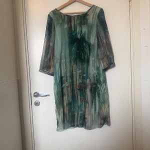 Grön mönstrad kortklänning  - Unik kortklänning i tunnt, flowy material med grönt och blått mönster som påminner om akvarell. Klänningen har trekvartsärm och rund halsringning. Perfekt för dig som gillar en chill och konstnärlig vibe. Från märket Cream. Mycket fint skick, jag hittar inga synliga anmärkningar eller defekter. 