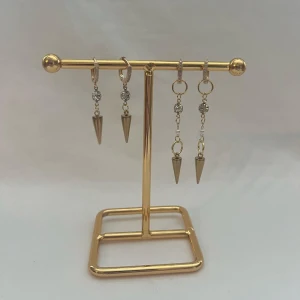 Silvriga örhängen med spetsig hängande detalj - Coola silvriga örhängen med hängande konformad spets och gnistrande stenar. Örhängena har små ringar och kedjor som ger en edgy vibe. Perfekt för dig som gillar att sticka ut med detaljer och glans.