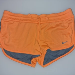 Orange träningsshorts från Nike - Modellen är loose fit med låg midja och har snörning i midjan. Materialet är lätt, perfekt för sport och aktivitet.