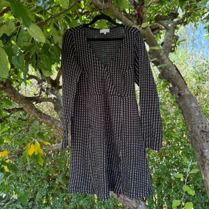 Svartvit randig klänning Cream L - Snygg svart klänning från Cream i storlek L med beige ränder och v-ringad hals. Modellen är kort och har långa ärmar, vilket ger en cool och avslappnad vibe. Materialet känns mjukt och följsamt, perfekt för dig som gillar bekväma och stilrena plagg. Mycket fint skick, jag hittar inga synliga anmärkningar eller defekter. 