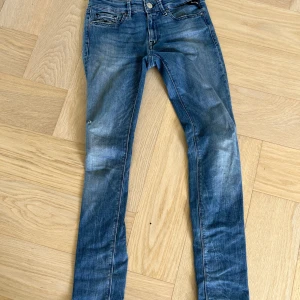 Replay Luz skinny jeans blå, stl 27 - Snygga Replay Luz jeans i klassisk blå tvätt med slitningar och skinny fit. Jeansen har fem fickor, låg midja och coola detaljer på bakfickorna. Materialet är mjukt denim med stretch för extra komfort.
