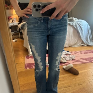 Ripped jeans - Snygga blå bootcut jeans från Gina Tricot med hål. Jeansen har klassisk femficksdesign, normal passform och är tillverkade i jeansmaterial. Perfekta för dig som gillar en avslappnad och trendig look. Helt ny köpta endas använda en gång