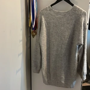 Grå stickad tröja från KappAhl - Mysig grå stickad tröja från KappAhl i storlek 158/164. Tröjan har en enkel, rak passform med rund halsringning och långa ärmar. Perfekt för kyliga dagar och lätt att matcha med jeans eller leggings. Lite längre än vanligt.