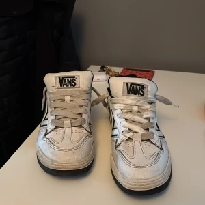 Vita sneakers från Vans med svart detalj - Säljer ett par vans sneakers som är ganska andvända men dem funkar ju att ha, det är storlek 43. Kan gå ner i pris!