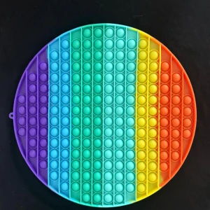 Rund regnbågsfärgad pop it-leksak - Säljer en stor rund pop it-leksak i regnbågens färger. Den har bubblor att trycka på och är perfekt för att stressa ner eller bara ha kul. Färgerna går i lila, blå, grön, gul, orange och röd. Gjord i mjuk silikon och lätt att ta med sig.