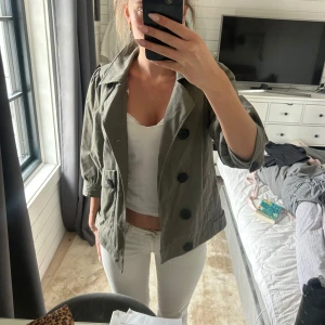 Olivgrön kavaj med stora knappar - Säljer en stilren olivgrön kavaj med stora svarta knappar. Kavajen har trekvartsärmar och en klassisk krage. Perfekt för en chic och avslappnad look. Pris går såklart att diskuteras💗💗