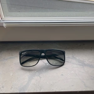 Solglasögon  - Snygga svarta solglasögon f med breda skalmar och rektangulära glas. Glasögonen har en matt finish och mörka tonade linser. Perfekta för en stilren look.